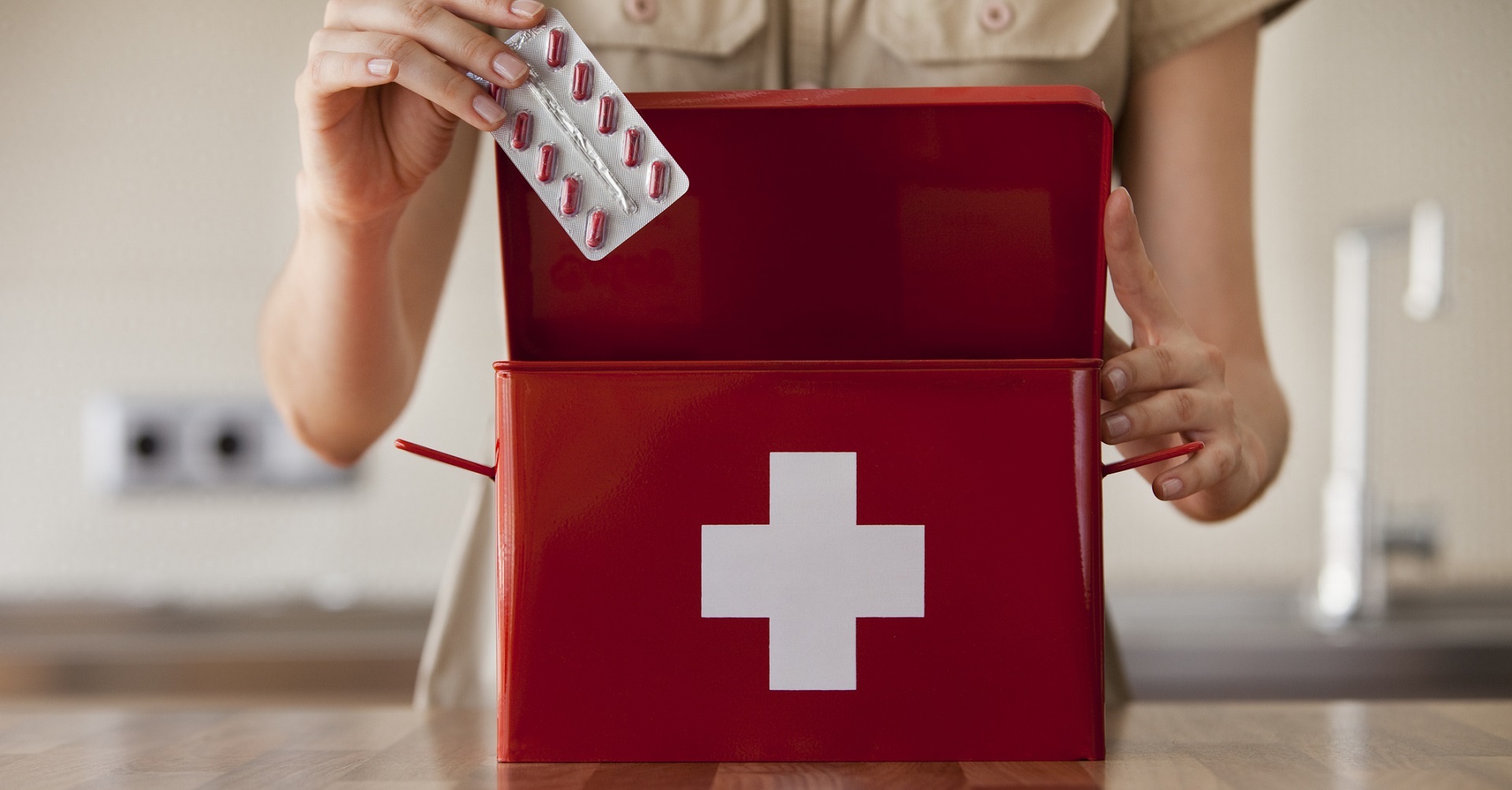 woman putting medicine into first aid kit