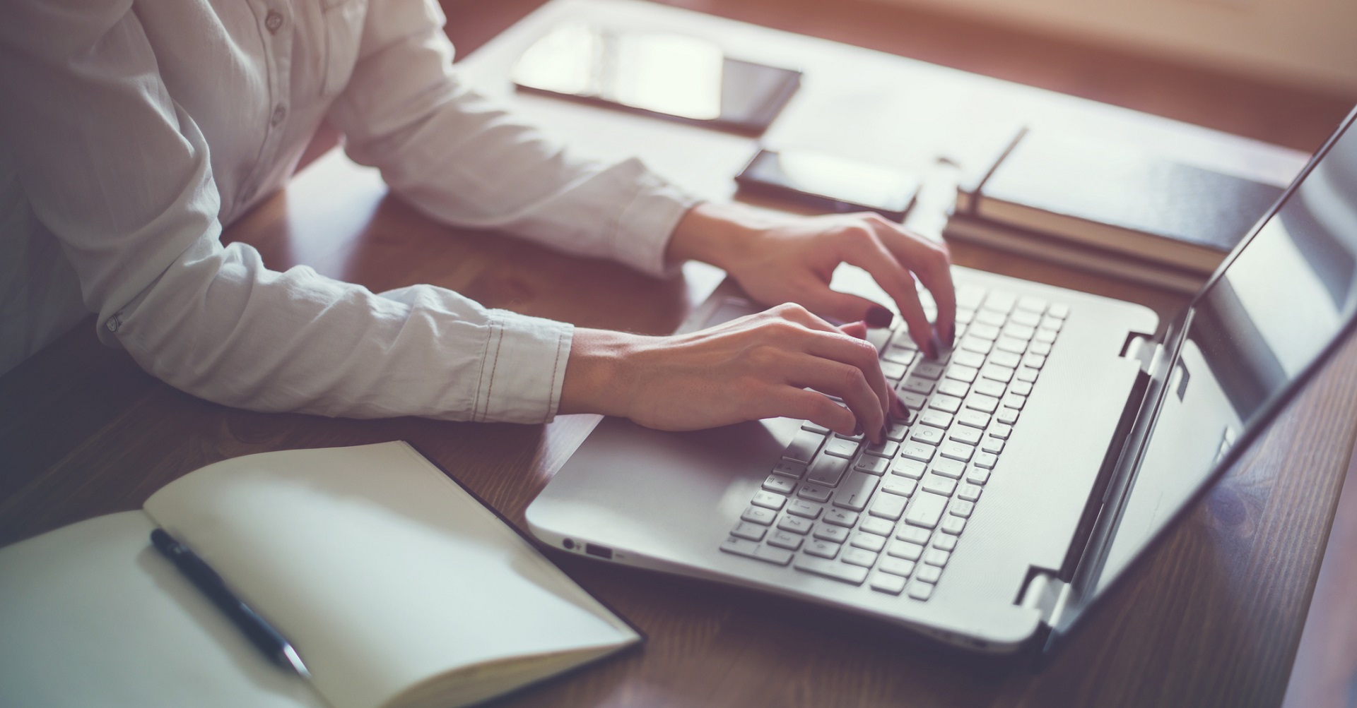 woman on laptop with notepad next to her