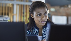 woman holding phone and looking at laptop