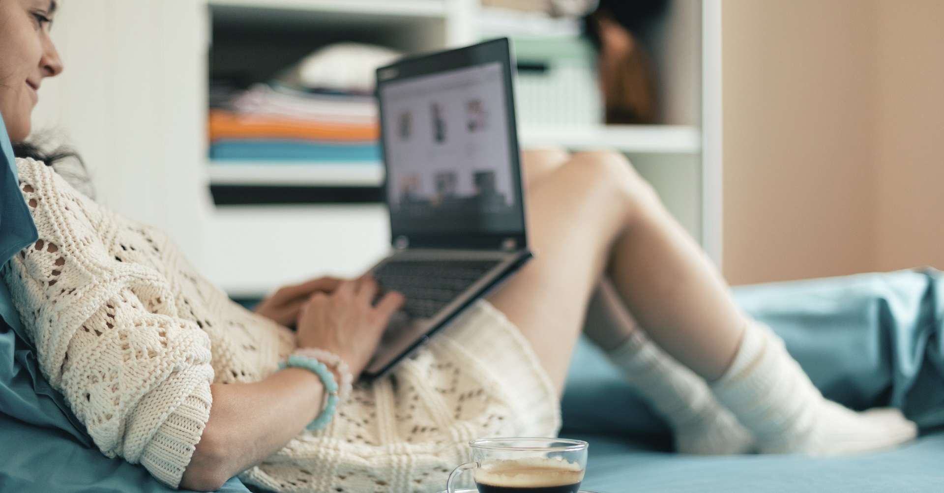 woman sitting on bed with laptop