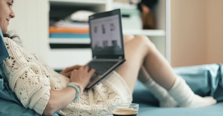 woman sitting on bed with laptop