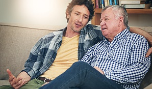 Adult son sitting on the couch talking to father