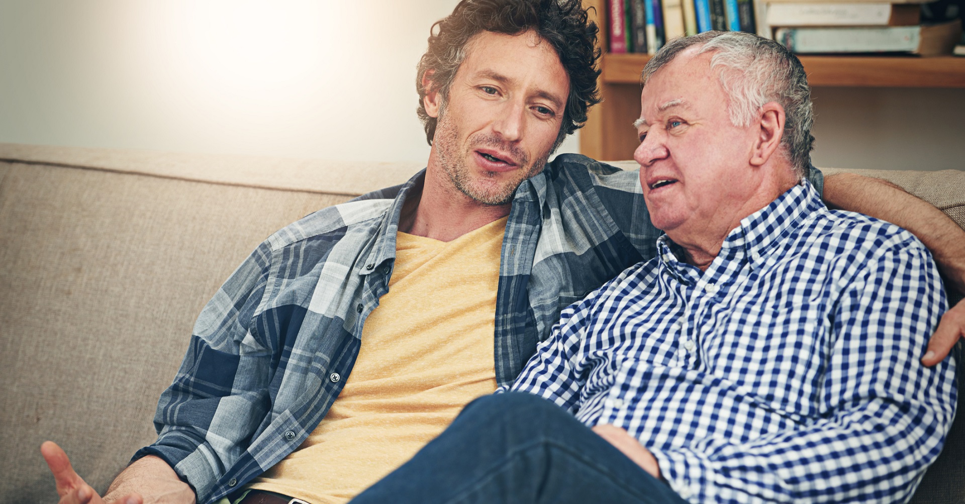 Adult son sitting on the couch talking to father