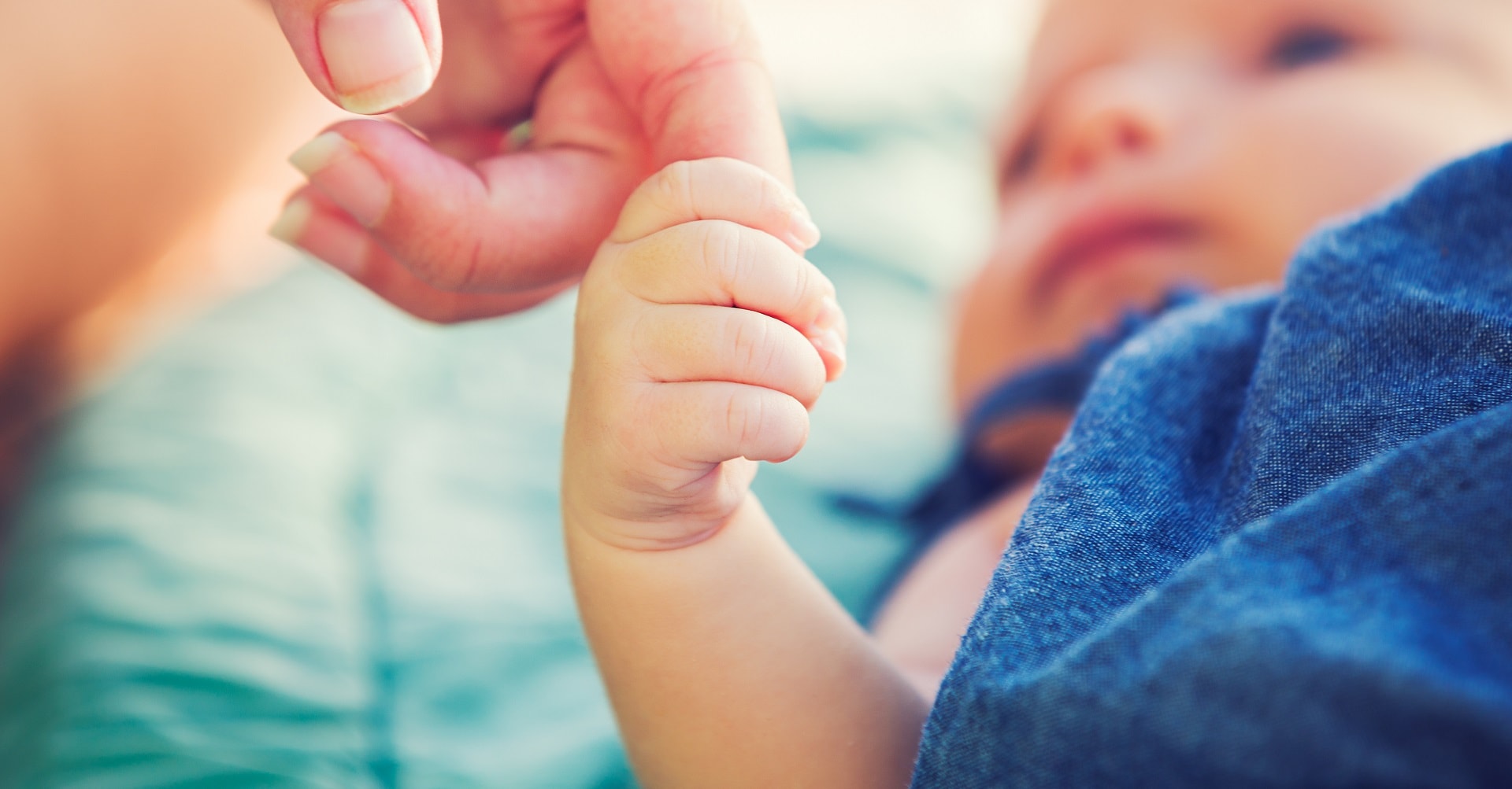 baby holding mother's finger