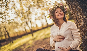 pregnant woman sitting on grass with flower crown