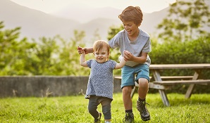 little boy playing with his sister in the garden