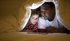 father lying in tent reading to son