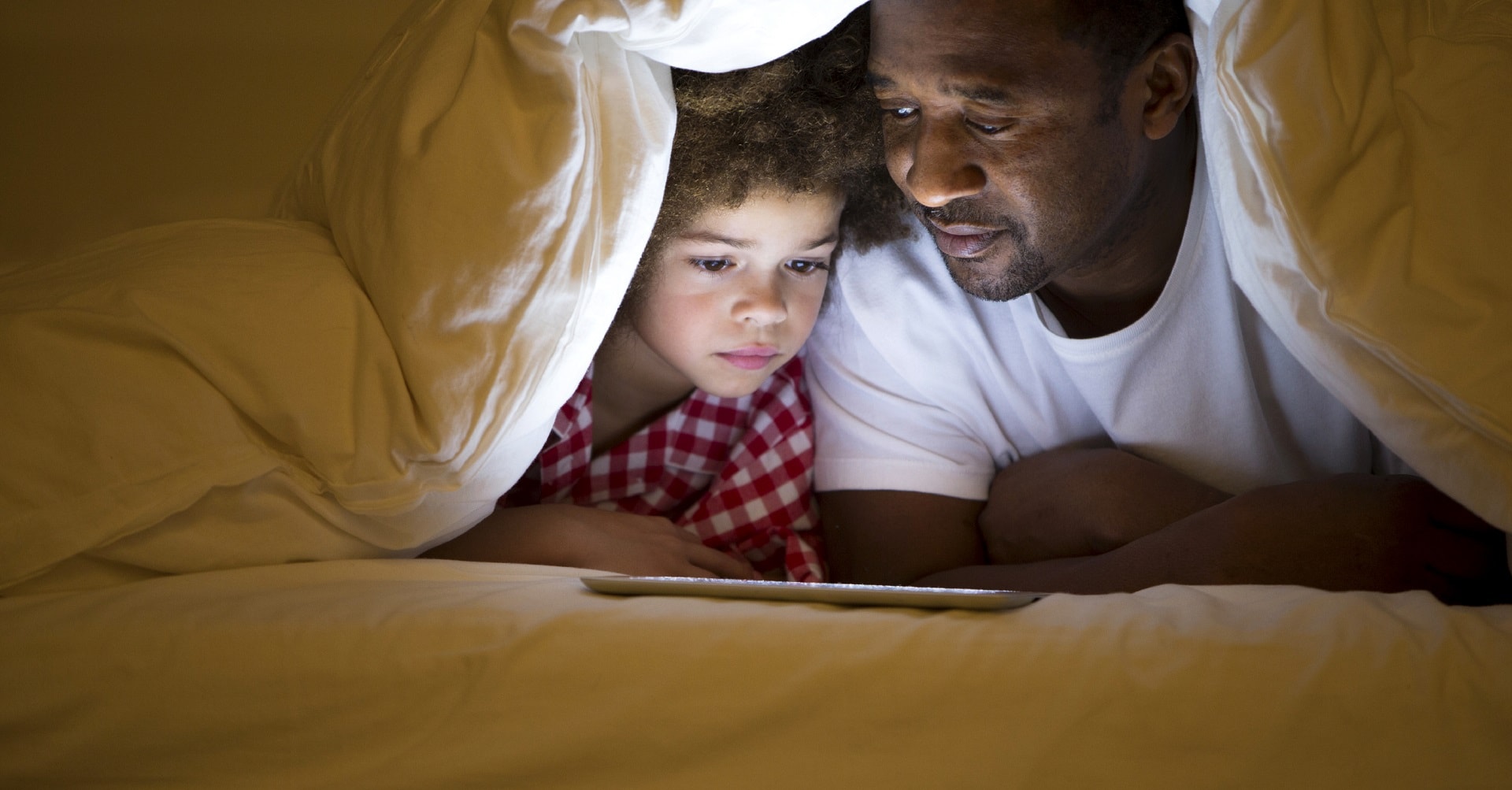 father lying in tent reading to son