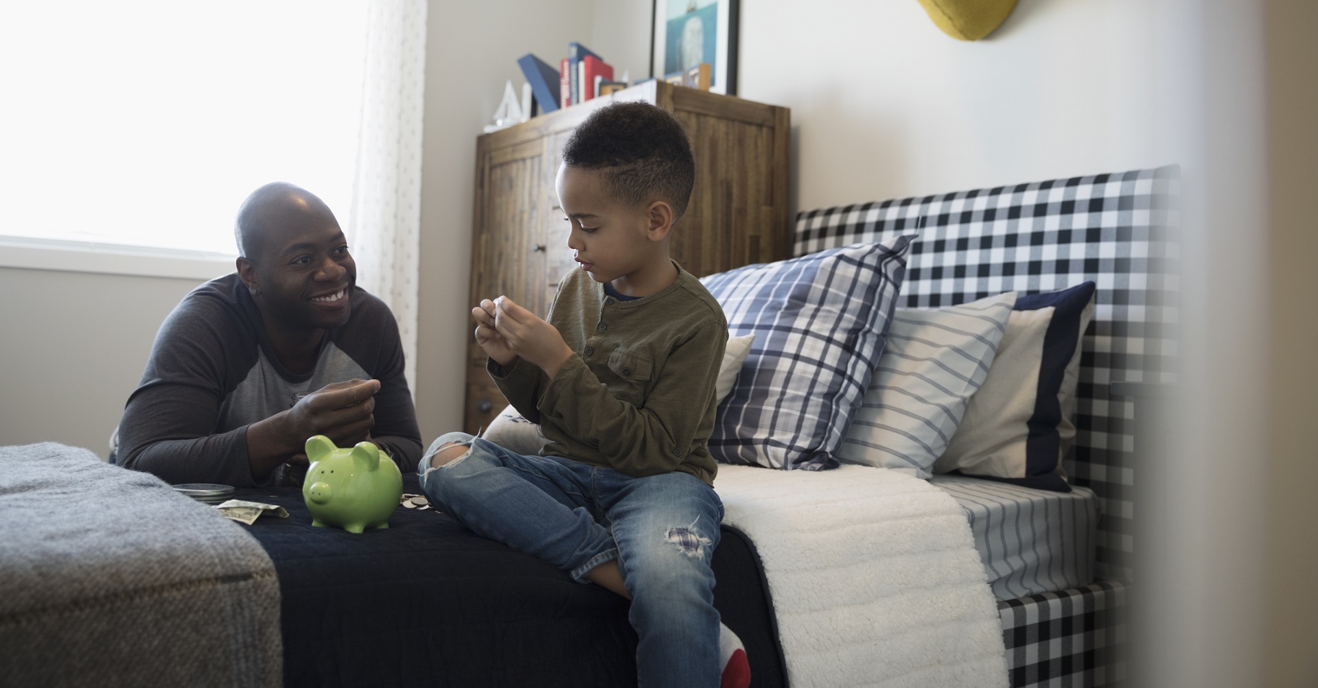 Father and son putting money into piggy bank