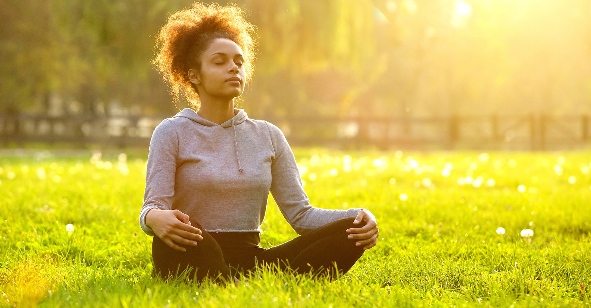 woman sitting on grass in the sun looking relaxed