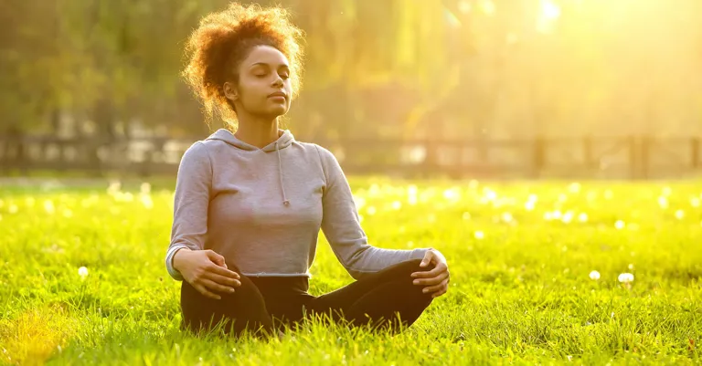 woman sitting on grass in the sun looking relaxed