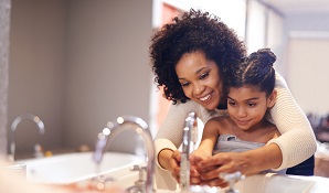 mother washing daughters hands in sink