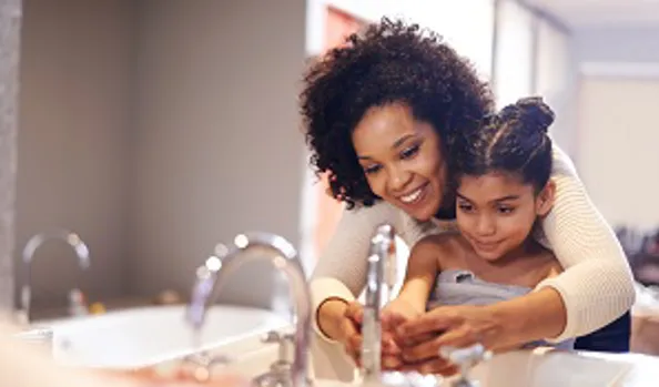 mother washing daughters hands in sink
