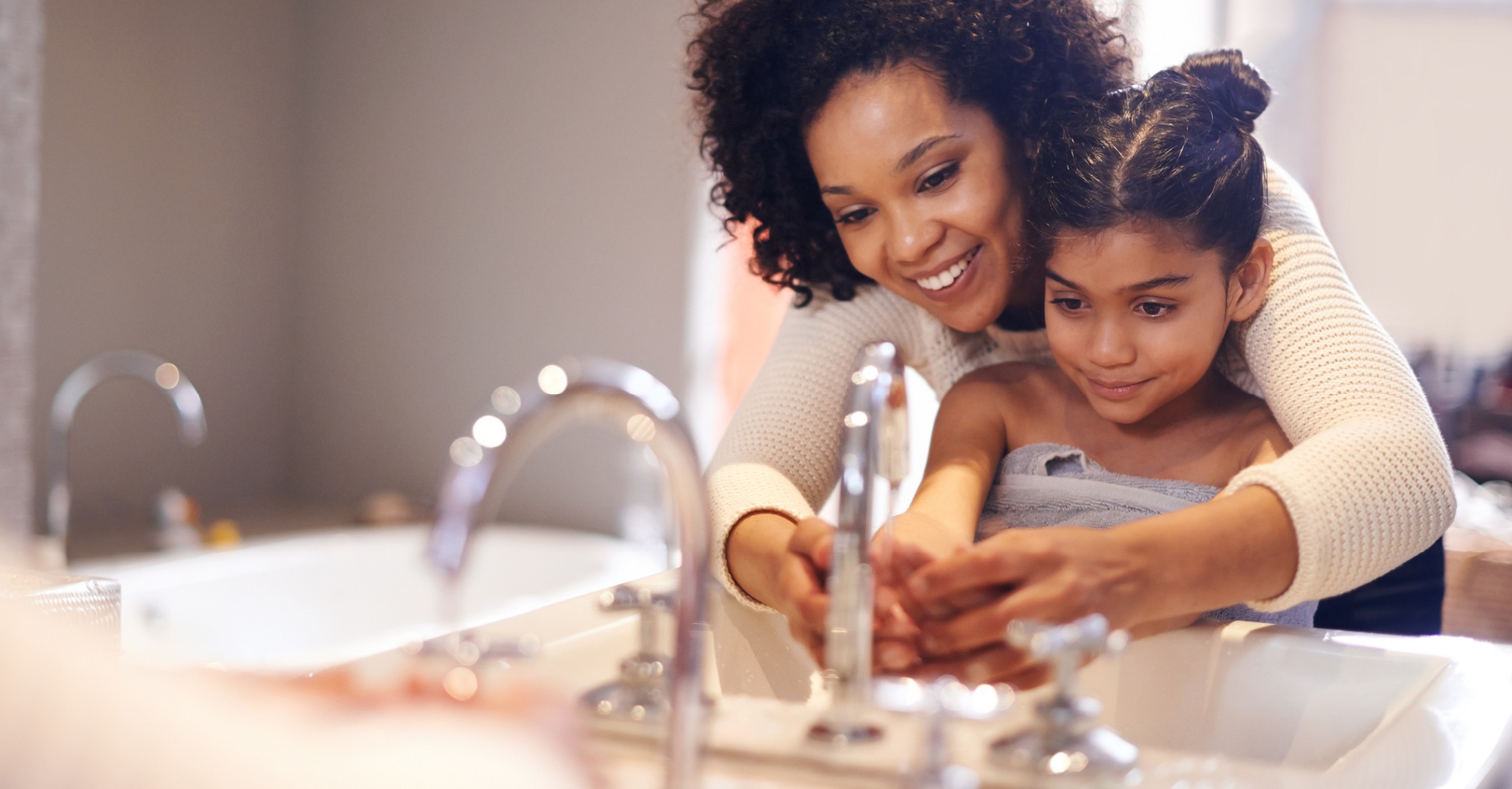 mother washing daughters hands in sink