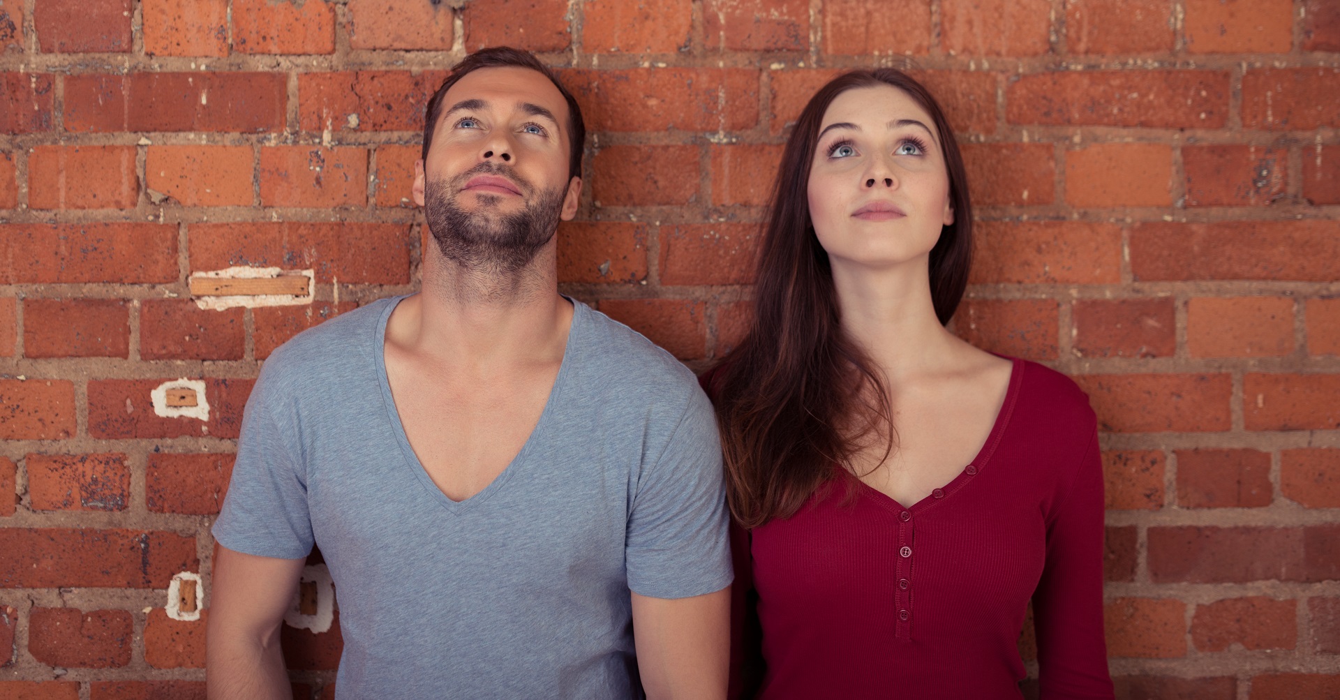 couple standing against wall looking up