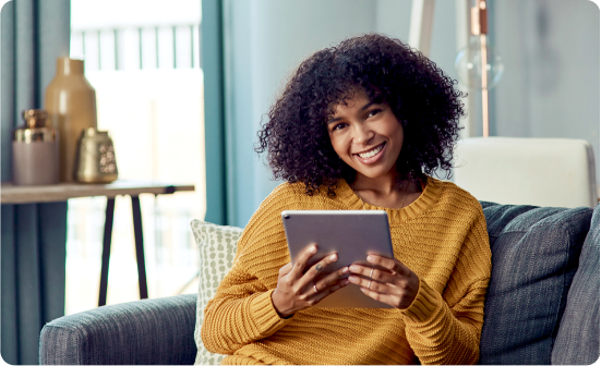 woman using a tablet, smiling, sitting on a couch
